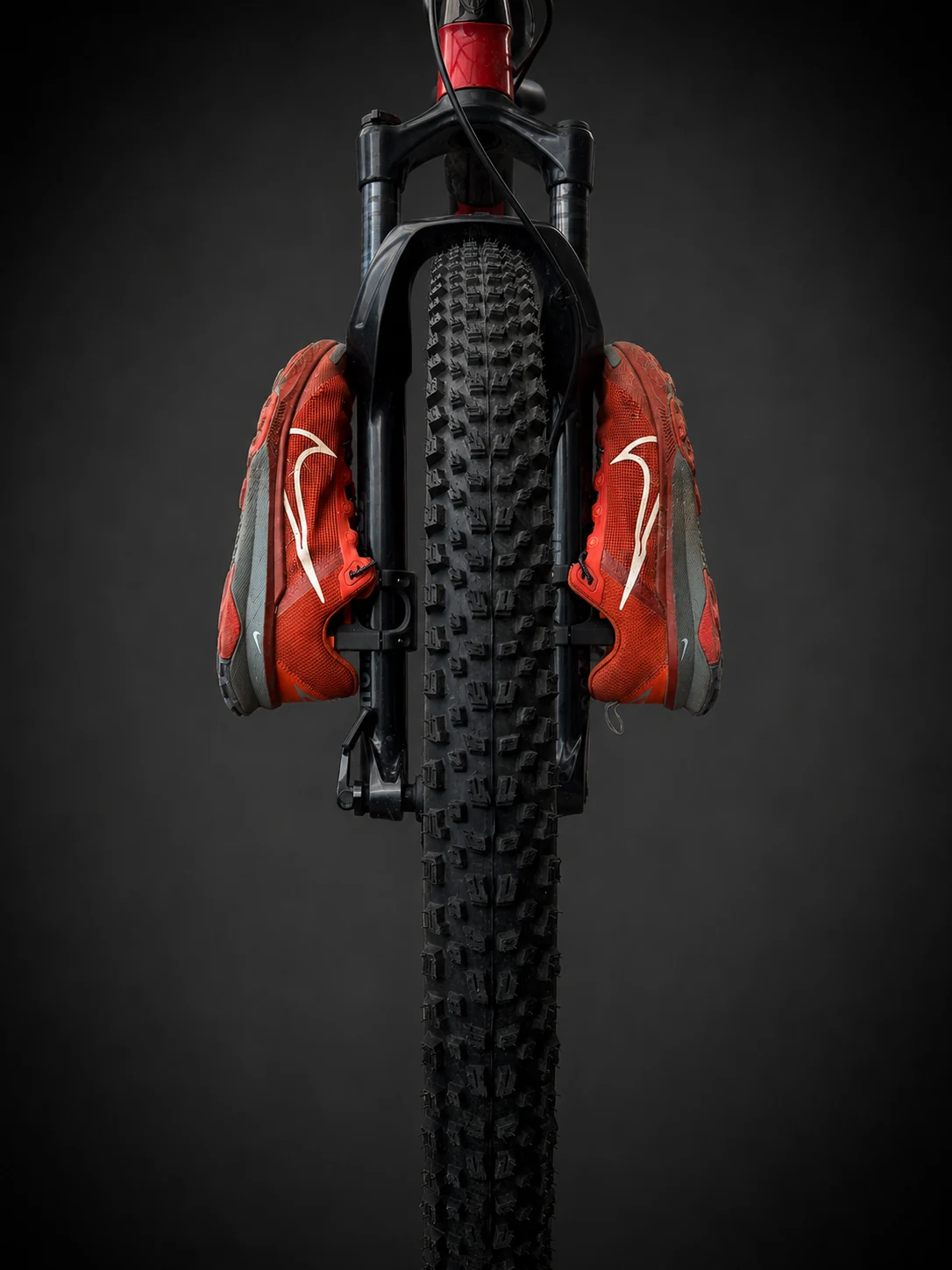 Deux chaussures fixées sur la fourche d’un VTT avec le kit FIXATRAX Porte-chaussures